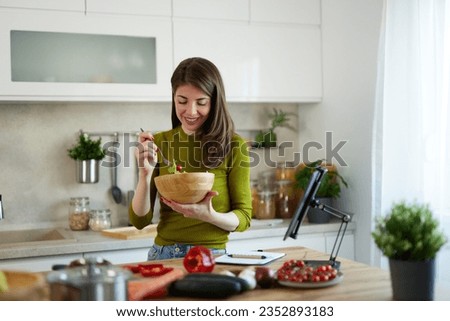 Cheerful vegeterian woman eating salad in the kitchen