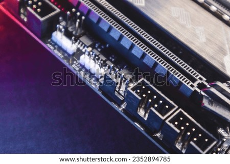 Motherboard with sockets and connectors close-up on powerful desktop PC in purple light. Computer hardware chipset components. Tech industry electronics background