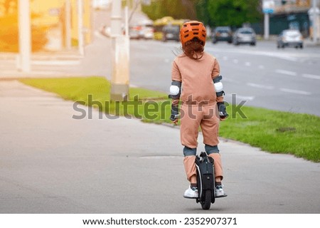 Woman in protective gear riding electric unicycle, monocycle or mono wheel. Trendy woman in helmet on electric vehicle, view from back. Woman ride electric mono wheel, personal electric transport Royalty-Free Stock Photo #2352907371