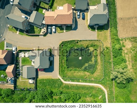 Aerial view of a new detached housing estate seen next to an attenuation pond.