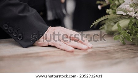 Death, funeral and hand on coffin in mourning, family at service in graveyard or church for respect. Flowers, loss and people at wood casket in cemetery with memory, grief and sadness at grave burial Royalty-Free Stock Photo #2352932431