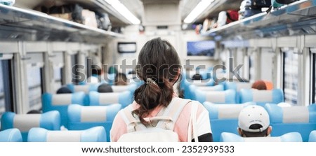 Beautiful young asian woman with backpack walking while looking for her passenger seat in train car aisle. Concept for Solo traveling, vacation, holiday, journey, trip. Royalty-Free Stock Photo #2352939533