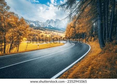 Road in mountains at sunny day in golden autumn. Dolomites, Italy. Beautiful roadway, orange tress, high rocks, blue sky with clouds. Landscape with empty highway through the mountain pass in fall Royalty-Free Stock Photo #2352941065