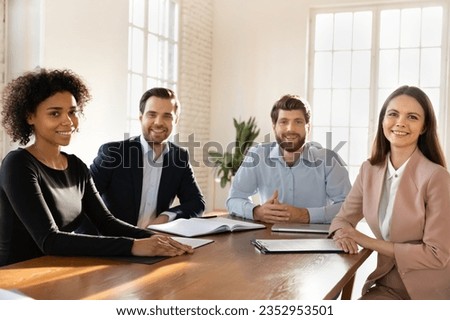 Group team portrait of smiling multiracial young businesspeople sit at desk in office, talk brainstorm at meeting together, happy motivated diverse colleagues employees cooperate at workplace Royalty-Free Stock Photo #2352953501