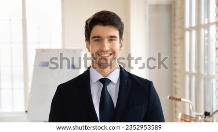 Close up headshot portrait of smiling young Caucasian businessman in formal suit look at camera posing in office, profile picture of male boss or employee show confidence success at workplace