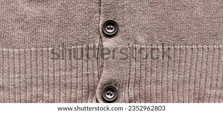 Patterned cardigan fabric made of wool. Handmade knitted fabric gray wool sweater background texture and gray buttons