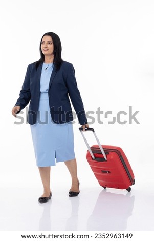 Full length of confident female professional manager with suitcase looking up and standing against white background