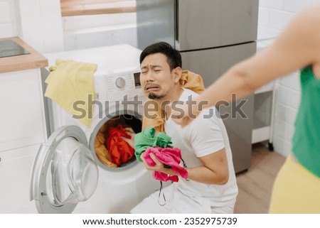 Funny asian man crying being force by his wife to wash clothes and do housework. Royalty-Free Stock Photo #2352975739