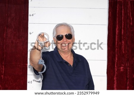 Photo Booth. A man Laughs and Smiles as his Mugshot Photos are taken during an arrest. A man Poses in a Photo Booth against a Mugshot Photo board. People love Photo Booth. Funny Photos. Pictures. 