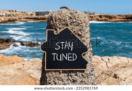 Stay tuned symbol. Concept words Stay tuned on beautiful black chalk blackboard on a beautiful beach stone background. Business, support, motivation, psychological and stay tuned concept. Copy space. Royalty-Free Stock Photo #2352981769