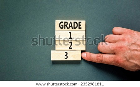 Time to grade 3 symbol. Concept word Grade 1 2 3 on wooden block. Businessman hand. Beautiful grey table grey background. Business planning and time to grade 3 concept. Copy space. Royalty-Free Stock Photo #2352981811