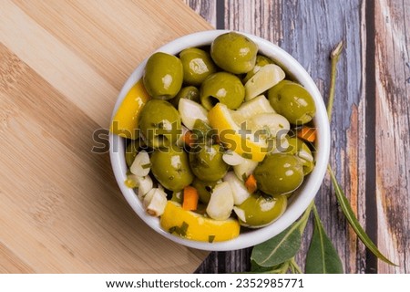 Marinated garlic pitted olives with lemon on a rustic wooden background - Selective focus