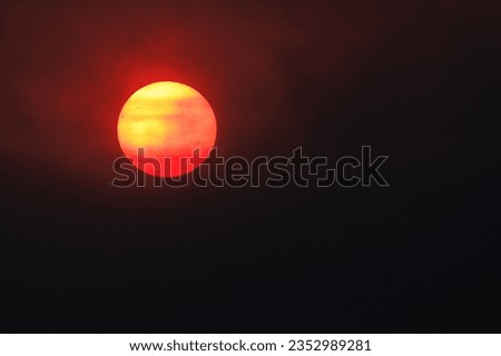 Red round sun covered by smoke from forest wildfire, close up shot, night view, wallpaper design.