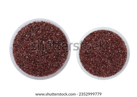 Overhead view of the tiny red Garnet mineral sands on two small plastic trays. This two transparent trays containing tiny red Garnet gravel pieces are in an isolated background Royalty-Free Stock Photo #2352999779