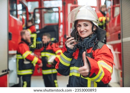 Beautiful fire fighter woman with her helmet standing in the firehouse Royalty-Free Stock Photo #2353000893