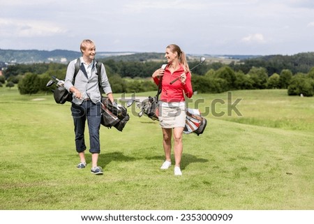 Golfing couple walking with shoulder bag on course Royalty-Free Stock Photo #2353000909