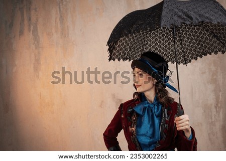 stylish lady in a burgundy old - fashioned suit with a hat and a lace umbrella . Brunette in a retro style suit Royalty-Free Stock Photo #2353002265