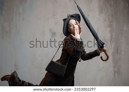 A stylish lady in an elegant Victorian-style suit, wearing a hat with an umbrella in her hands Royalty-Free Stock Photo #2353002297