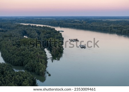 Aerial photo of the cargo ships on the Danube River near the border of Hungary and Croatia, next to the forest. Aerial shot.