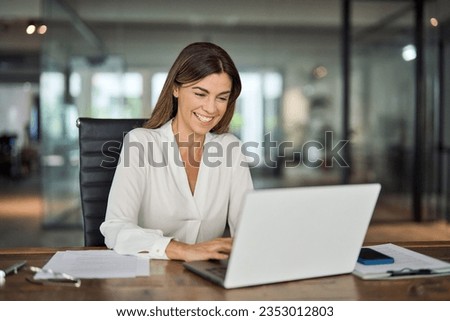 Happy cheerful mid aged business woman executive in office using laptop at work, smiling professional mature 40 years old female company manager working on computer at workplace. Royalty-Free Stock Photo #2353012803