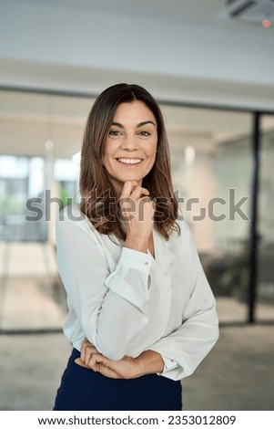 Happy cheerful confident Latin professional mid aged business woman in 40s, corporate leader, happy mature female executive, lady manager standing in office looking at camera, vertical portrait. Royalty-Free Stock Photo #2353012809
