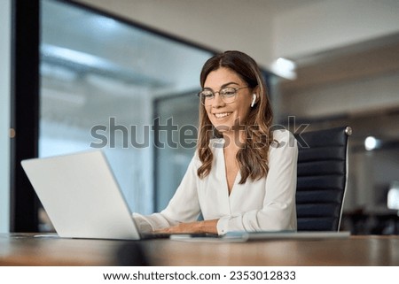 Happy mid aged business woman having hybrid meeting working in office. Busy mature female corporate leader executive, hr manager communicating by conference call, remote online job interview on laptop Royalty-Free Stock Photo #2353012833