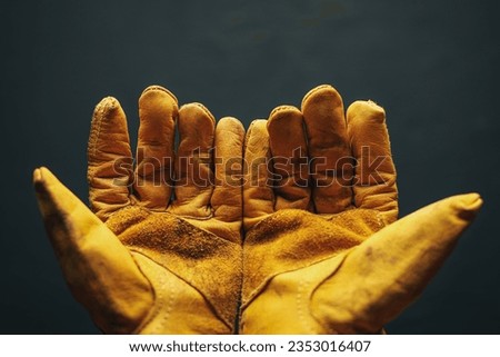 Open hands reaching out wearing an old worn work gloves. Employment for blue collar workers, fair pay, or Labor Day concept. Royalty-Free Stock Photo #2353016407