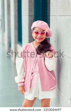 Portrait of cute smiling girl in pink outfit and sunglasses in town