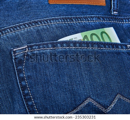 100 Euro bill sticking out from a blue jean pocket. Closeup