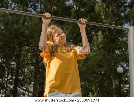 The girl tries to rise on her hands on the horizontal bar, but does not have enough strength. Poor health Royalty-Free Stock Photo #2353091971