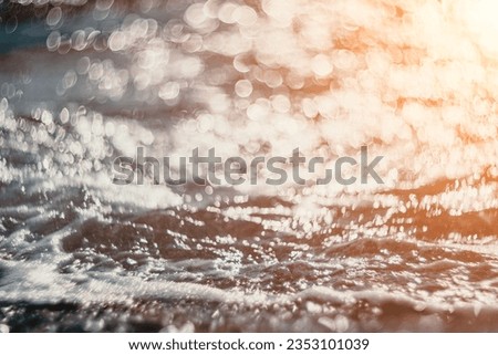 Abstract nature summer ocean sunset sea background. Small waves on water surface in motion blur with bokeh lights from sunrise. Holiday, vacation and recreational background concept.
