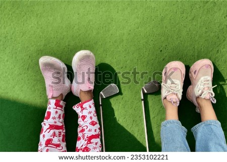 This is a picture of children Spend time playing sports. is golf wearing sneakers go on golf course green lawn It is relaxing in lifestyle