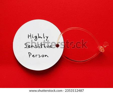 Tag on red background with handwritten text HIGHLY SENSITIVE PERSON, refers to people who think and feel everything more deeply, more sensitive to the environment and social interactions Royalty-Free Stock Photo #2353112487
