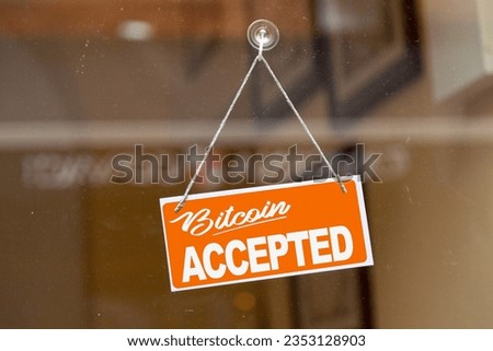 Orange sign hanging at the glass door of a shop saying: "Bitcoin accepted".