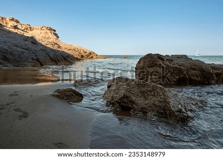 Beautiful seascape with wide-angle shot of the exit from a cave with the sea and the shore of the beach in the foreground, the sea to the horizon in the background and to the right a rock that merges 