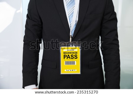 Midsection of businessman wearing backstage pass in office