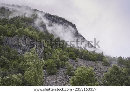 Landscape picture of norwegian mountains with rocks, stones and heavy clouds on the top taken during rainy and foggy morning. Typical weather conditions for late summer in the scandinavian mountains. 
