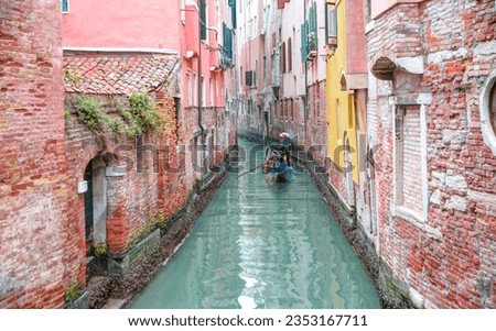 Venetian gondolier punting gondola through green canal waters of Venice Italy Royalty-Free Stock Photo #2353167711