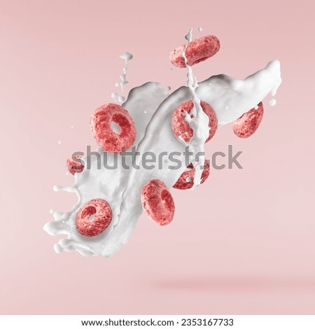 Tasty pink ring Cereals with milk splashes falling in the air isolated on pink background. Food levitation conception. High resolution image