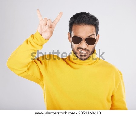 Man, sunglasses and horns sign in studio portrait, rock icon or hand gesture with clothes by white background. Young guy, model and devil fingers for attitude, fashion or crazy with emoji for culture