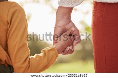 Mother, kid and holding hands for walking in park for support, trust and care together or bonding in nature. Love, comfort and parent help child in the morning sunshine with kindness on weekend Royalty-Free Stock Photo #2353169635