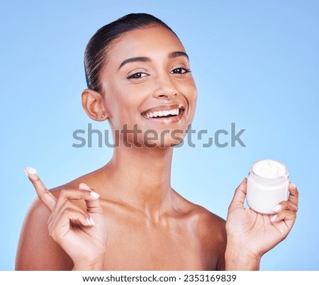 Cream jar, portrait and woman in studio with facial product for aesthetic skincare, dermatology or smile on blue background. Happy indian model, face lotion and glow of cosmetics container for beauty Royalty-Free Stock Photo #2353169839
