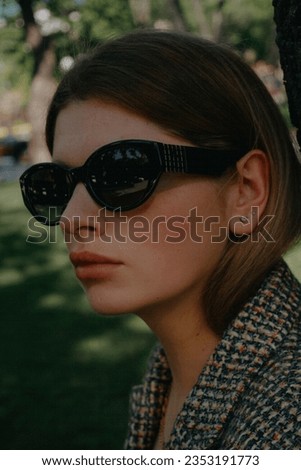 beautiful fair-haired woman in black glasses, jacket, posing for the camera. Woman close-up. Street style shot of a beautiful young woman.