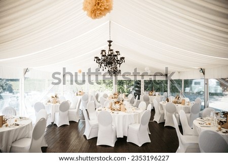 A spacious outdoor banquet tent with pristine white tablecloths and seating for a large group of people Royalty-Free Stock Photo #2353196227