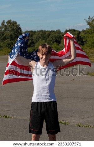 A happy and laughing teenage boy waving the American Flag