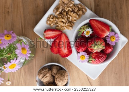 Healthy breakfast or snack with fresh strawberries, walnuts and daisies