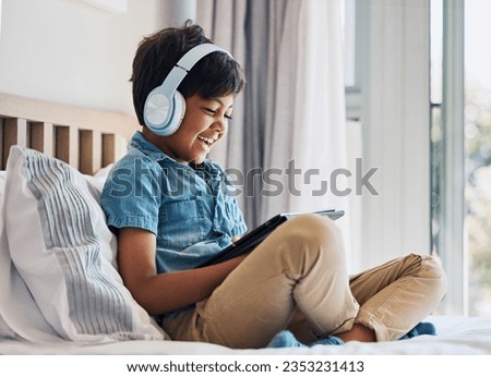 Happy, child and headphones with tablet on bed to watch funny movies, play video games or app. Boy kid laughing with digital technology for multimedia, listening to music or streaming cartoon at home