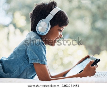 Boy, tablet and headphones on bed, smile and reading with idea, e learninng and movies on web to relax. Male kid, digital touchscreen and thinking in bedroom for games, music and streaming in home