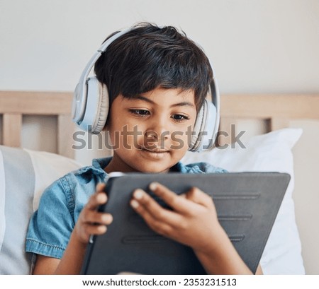 Face of boy, headphones and tablet in home for reading ebook, watch cartoon and play video games on elearning app. Child, kid and listening to multimedia, music and streaming movies on digital tech