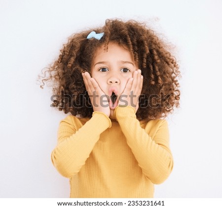 Child, shock and hands on face in studio for wow, surprise or announcement for sale or promotion. Face portrait of a young girl isolated on a white background with mouth open, news and omg emoji Royalty-Free Stock Photo #2353231641